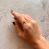 Mano con anillo dorado en forma de ola en el dedo índice