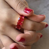 Mano con dedos entrelazados y un anillo con piedras grandes de color rubí