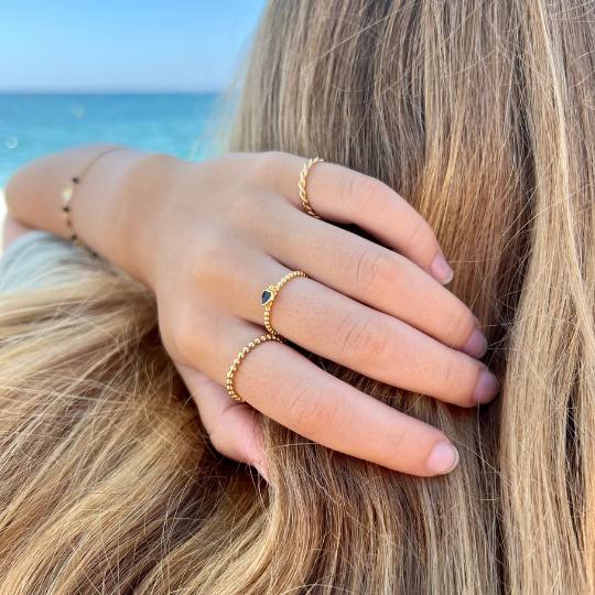 Chica tocándose el pelo con 3 anillos dorados de bolitas