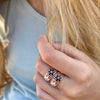 Mujer tocando el pelo con dos anillos de filigrana de plata, oro rosa y flores de esmalte