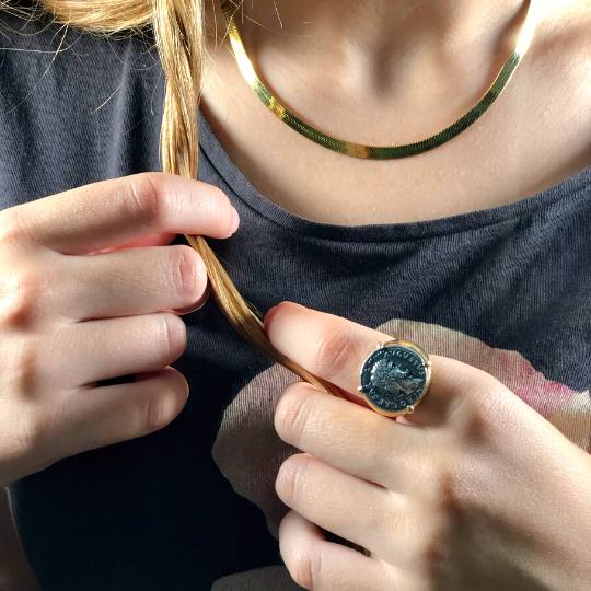 Mujer tocándose el cabello con un anillo sello con moneda