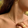 Escote de mujer con collar de prismas dorado, anillo minimalista y pendiente de aro