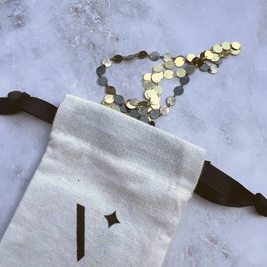 Bolsa de algodón con collares de placas doradas y negras