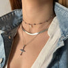 Escote de mujer con combinación de collares de plata y cadena con colgante de cruz con piedras de colores