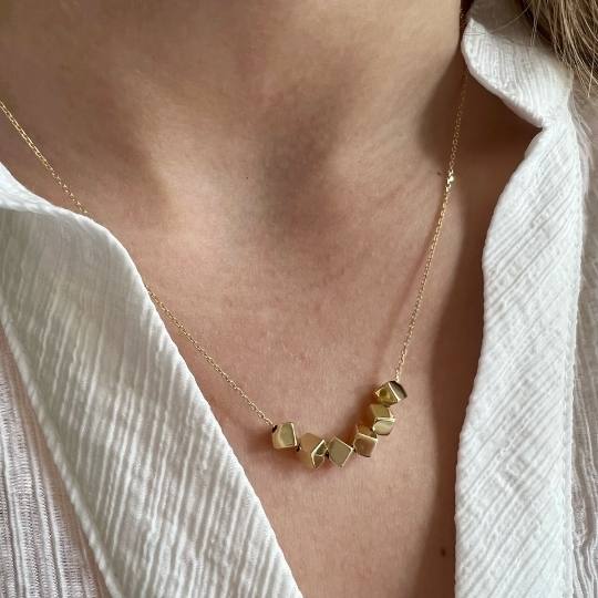 Cuello de mujer con collar dorado con seis cubos