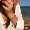 Mujer en la playa tocándose un pendiente con tres pulseras de bolas de plata