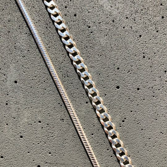 cadena barbada de plata y cadena de cola de topo sobre fondo gris