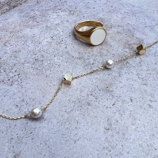 Pulsera con perlas y cubos dorados y un anillo dorado y blanco