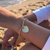 Mujer en la playa con pulsera dorada en forma de corazón