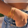 Mano de mujer metida en un bolsillo con dos pulseras doradas